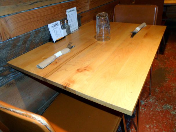 Close up of a small commercial quality Maple Table Top dining table slanted to the right at a restaurant bar.
