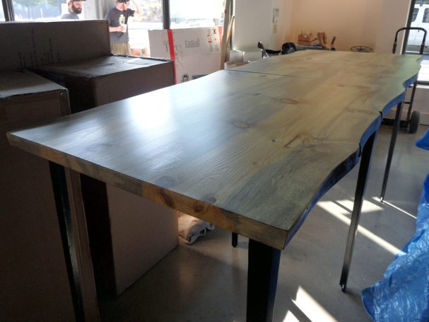 Large commercial quality Blue Pine Live Edge Slab Table Top dining table slanted to the right at a restaurant bar.