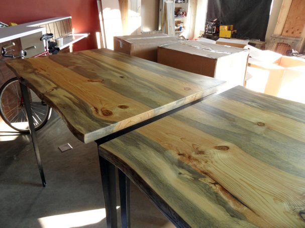 Closeup of two commercial Blue Pine Live Edge Slab Table Top dining tables slanted to the left at a restaurant bar.