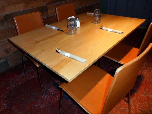 Commercial quality 4' Maple Table Top dining table slanted to the right at a restaurant bar.