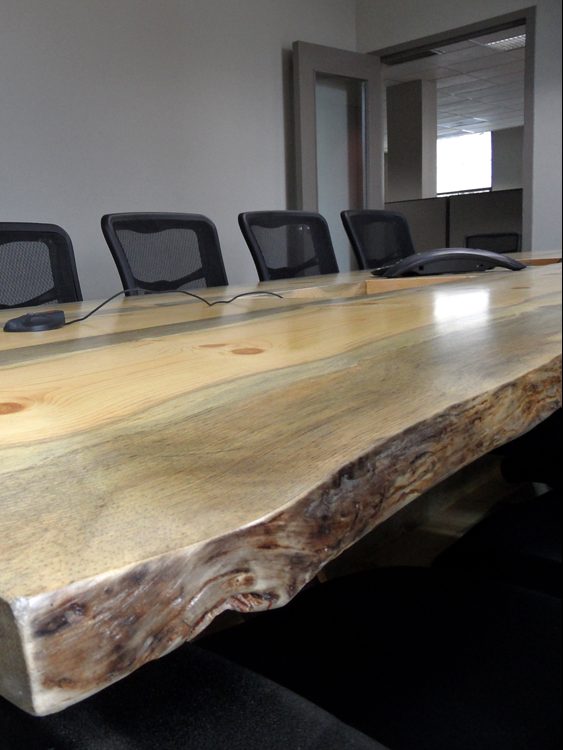 Close up of a Live Edge Blue Pine Slab Conference Table with reclaimed antique machinery bases slanted to the right.