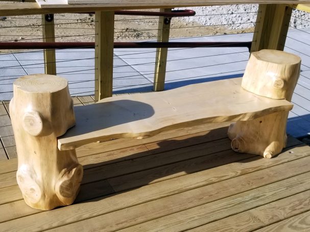 Handcrafted Pine Log Live Edge Slab Bench on the patio at High Grain Brewery slightly slanted to the right.