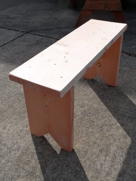 Medium Commercial quality eco-friendly Outdoor Farmhouse Bench slanted to the right on a sidewalk.