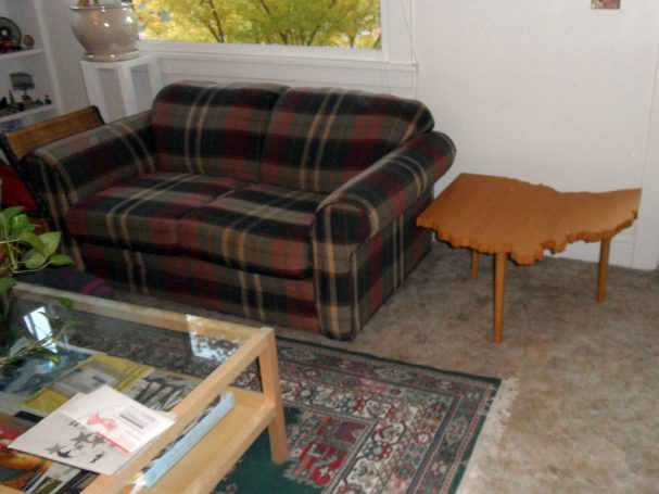 Luxury Handcrafted Douglas Fir Ohio Shaped End Table slanted slightly to the left next to a couch.
