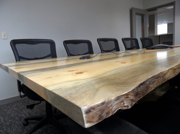 Close up of a Live Edge Blue Pine Slab Conference Table with reclaimed antique machinery bases slanted to the right.
