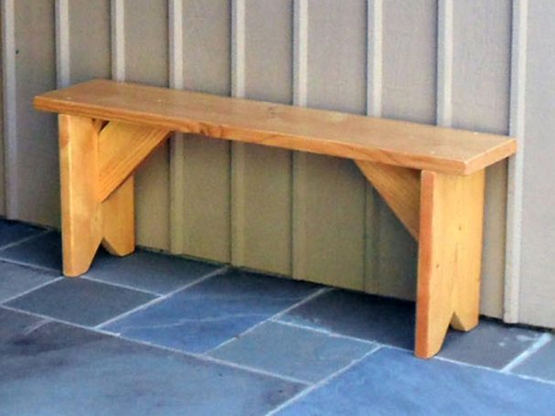 Commercial quality eco-friendly Outdoor Farmhouse Bench slanted to the left on a patio.