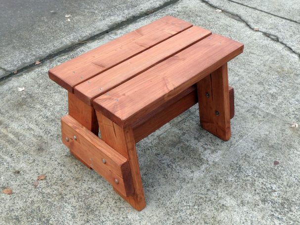 Commercial quality eco-friendly Outdoor Picnic Table Bench slanted to the right on the sidewalk.