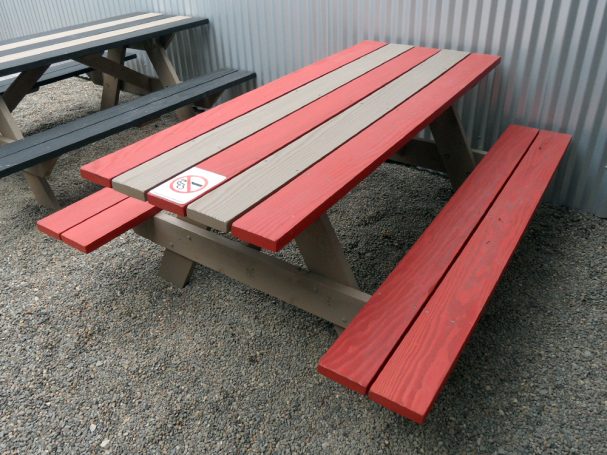 Striped red and gray Commercial quality eco Outdoor Attached Bench Picnic Table slanted right on a restaurant bar patio.