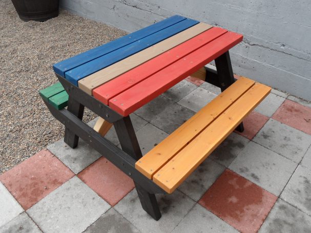 Multicolored Commercial quality Eco-friendly Outdoor Kids Attached Bench Picnic Table slanted to the right on a sidewalk.