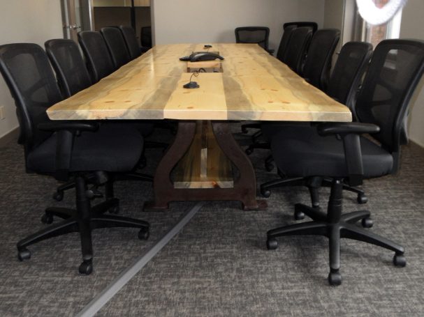 View of under a Custom Live Edge Blue Pine Slab Conference Table with reclaimed antique machinery bases.