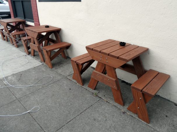 Small Commercial quality Custom Eco-friendly Outdoor Hybrid Bench Picnic Tables in a row on a restaurant bar sidewalk.