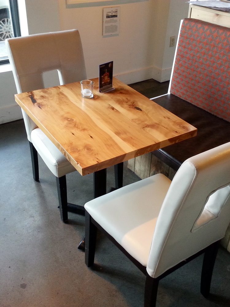 Three dining tables with commercial quality Handcrafted Juniper Table Tops slanted to the left inside a restaurant bar.