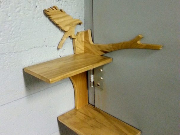 Close up of a Handcrafted Poplar Bird and Tree Corner Shelf hanging in the corner slanted to the left.