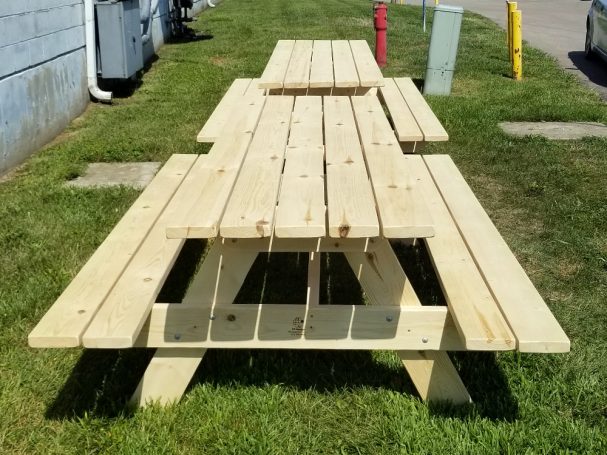 Two Large Commercial quality eco-friendly Outdoor Attached Bench Picnic Tables from the front in a break area.