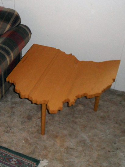 Luxury Handcrafted Douglas Fir Ohio Shaped End Table slanted slightly to the left next to a couch on a gray carpet.