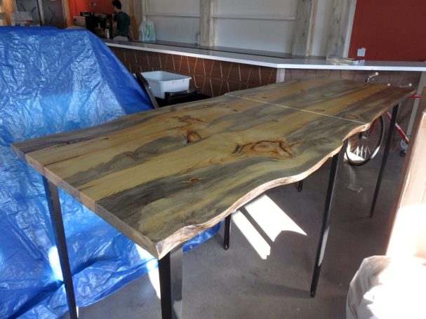 Two-part commercial quality Blue Pine Live Edge Slab Table Top dining table slanted to the right at a restaurant bar.