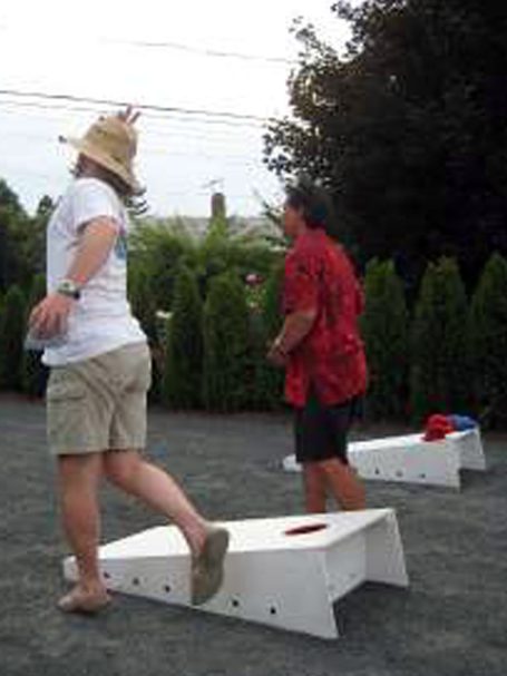 Back of people playing a cornhole tournament on back-to-back sturdy high quality solid box design Cornhole Board Sets.