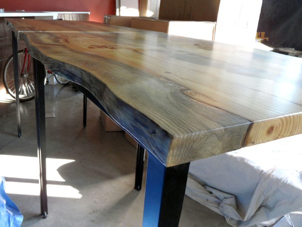 Closeup of commercial quality Blue Pine Live Edge Slab Table Top dining table slanted to the left at restaurant bar.