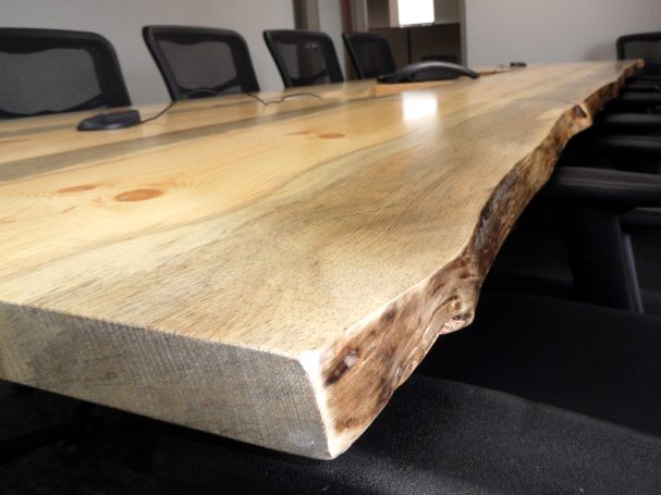 Close up of a Live Edge Blue Pine Slab Conference Table with reclaimed machinery bases slanted slightly to the right.