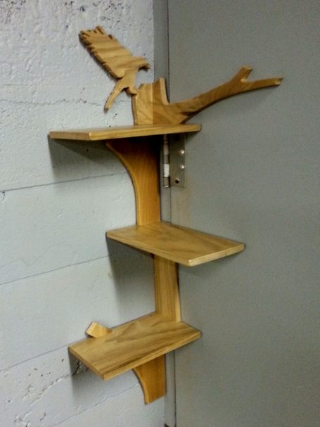 View of a Handcrafted Poplar Bird and Tree Corner Shelf hanging in the corner slanted to the left.