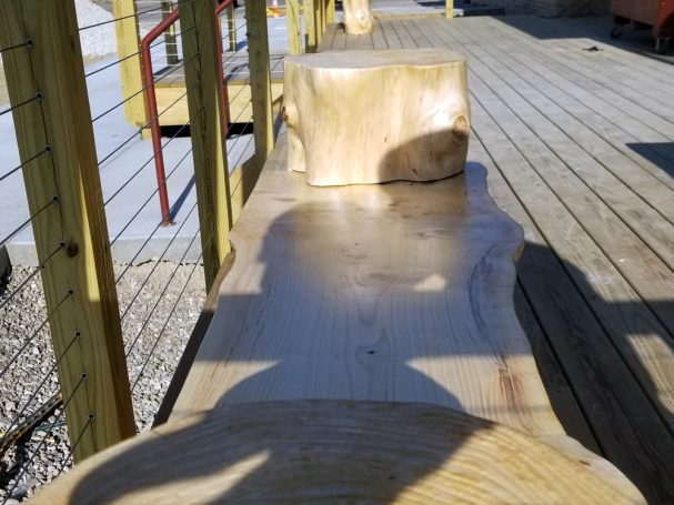 Close up of Handcrafted Pine Log Live Edge Slab Bench on the patio at High Grain Brewery from the side.
