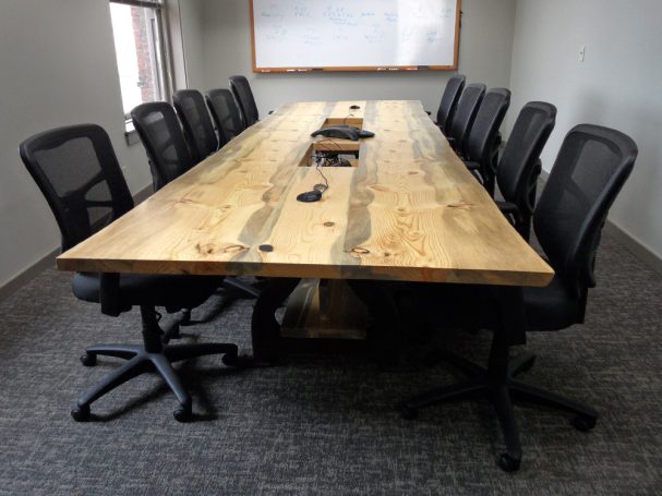 Back of a Custom Live Edge Blue Pine Slab Conference Table with reclaimed antique machinery bases.