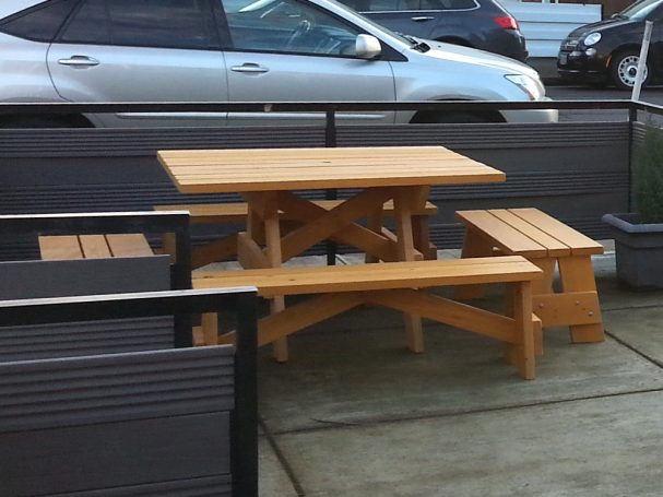 Commercial quality Eco-friendly Outdoor Square Detached Bench Picnic Table with four benches on a restaurant bar patio.