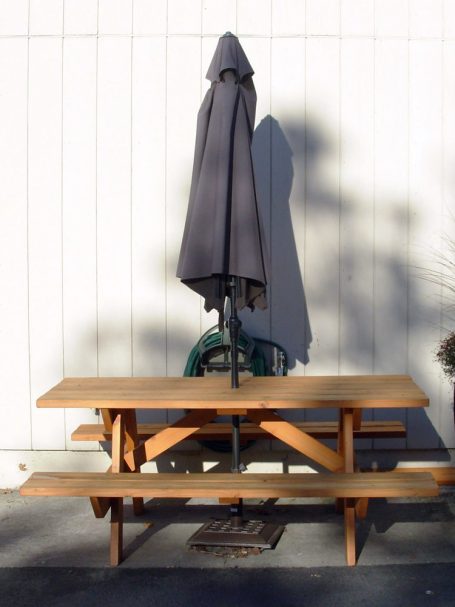 Commercial quality eco-friendly Outdoor Attached Bench Picnic Table with an umbrella from the side in a break area.