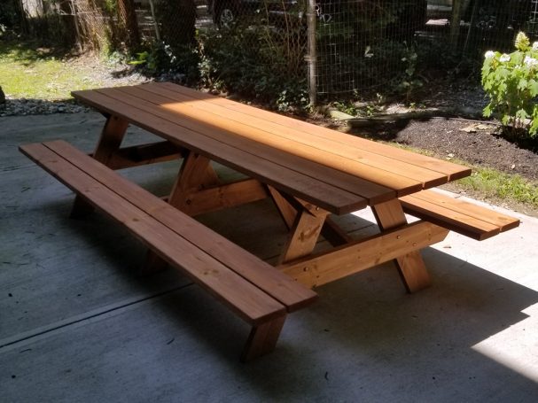 Large Commercial quality eco-friendly Outdoor Attached Bench Picnic Table slanted to the left on a patio.