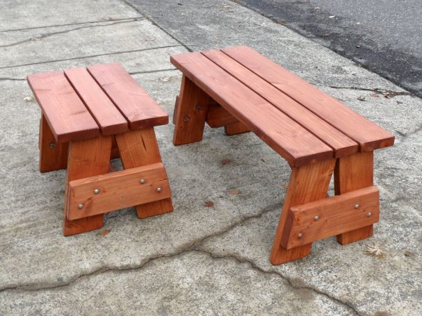 A short and a medium Commercial quality eco-friendly Outdoor Picnic Table Bench slanted to the left on the sidewalk.