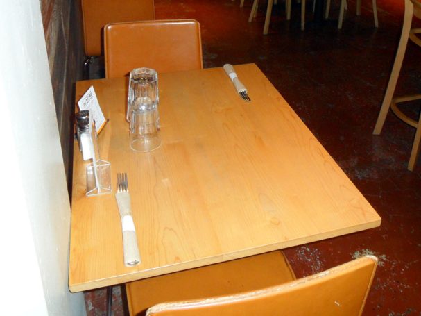 Close up of a small commercial quality Maple Table Top dining table slanted to the left at a restaurant bar.
