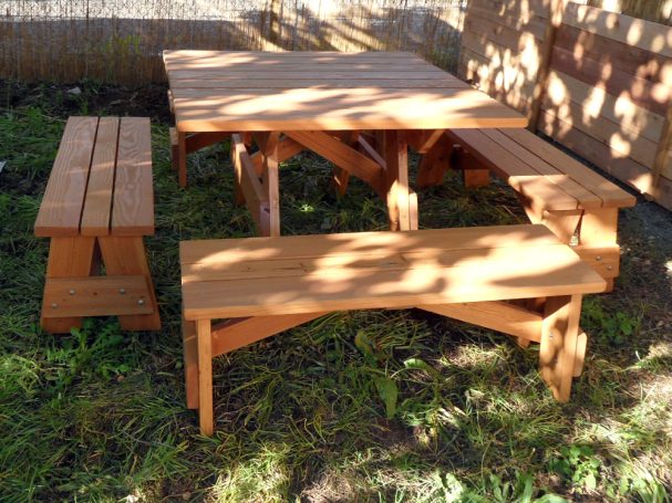 Commercial quality Eco Outdoor Square Detached Bench Picnic Table with four benches slanted slightly left in a backyard.