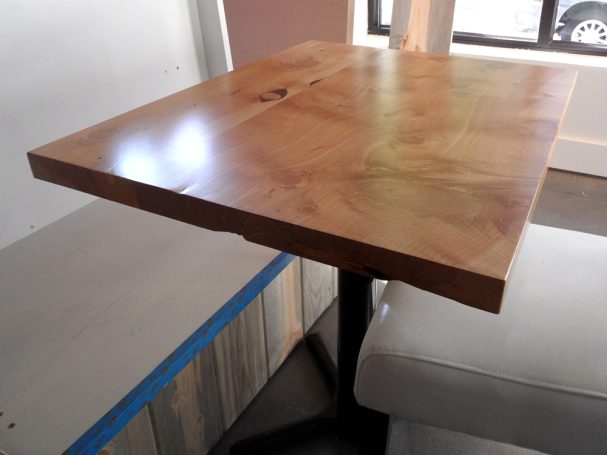 Close up of a commercial quality Handcrafted Juniper Table Top dining table slanted to the right at a restaurant bar.