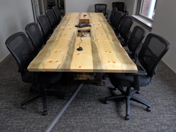 Front of a Custom Live Edge Blue Pine Slab Conference Table with reclaimed antique machinery bases.