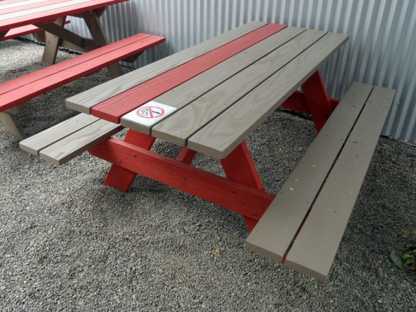 Red and gray Commercial quality eco Outdoor Attached Bench Picnic Table slanted right on a restaurant bar patio.