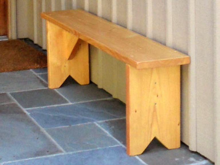 Commercial quality Outdoor Farmhouse Bench slanted to the right on the sidewalk outside a barbershop.
