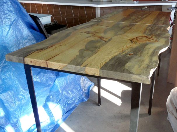 Closeup of two-part commercial Blue Pine Live Edge Slab Table Top dining table slanted to the right at a restaurant bar.