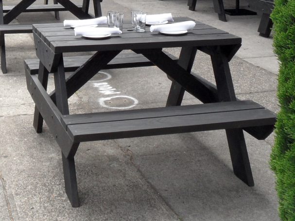 4' Commercial quality eco-friendly Outdoor Attached Bench Picnic Table slanted right on a sidewalk at a restaurant bar.
