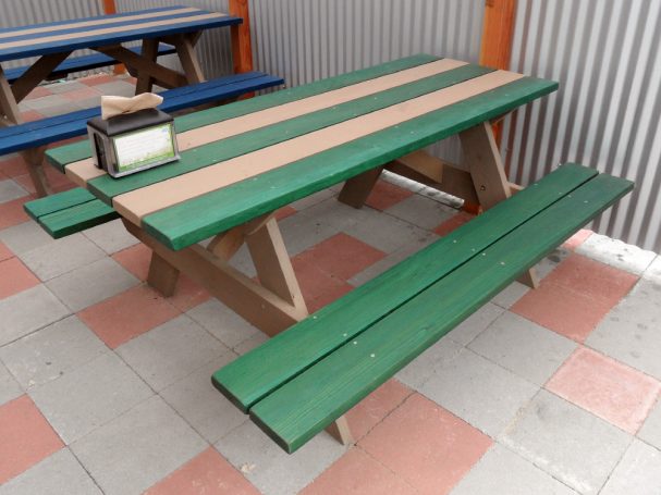 Striped green and gray Commercial quality eco Outdoor Attached Bench Picnic Table slanted right on restaurant bar patio.