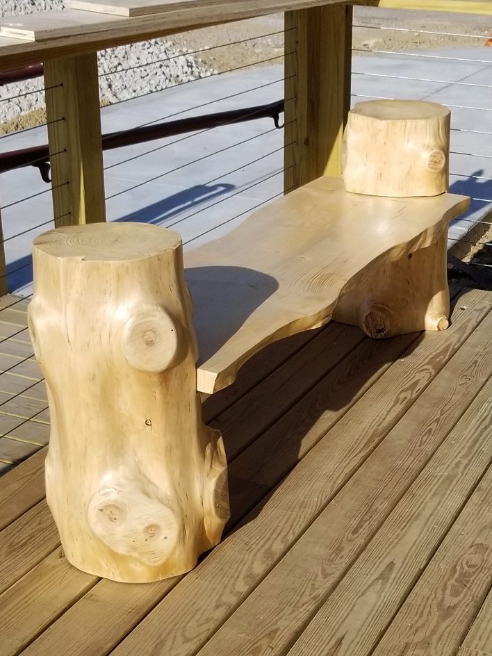 Handcrafted Pine Log Live Edge Slab Bench on the patio at High Grain Brewery slightly slanted to the right.