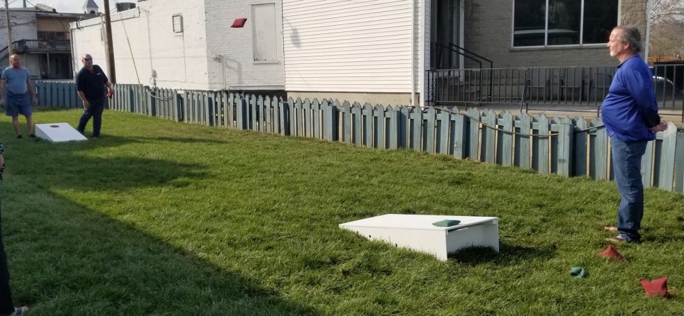 People playing cornhole on a sturdy high quality solid box design Cornhole Board Set in a side lawn.