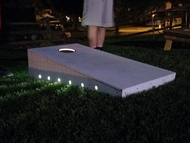 Sturdy high quality solid box design Cornhole Board in a yard over a light to play at night.